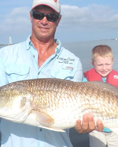 Captain Chuck holding a bull redfish aboard his boat