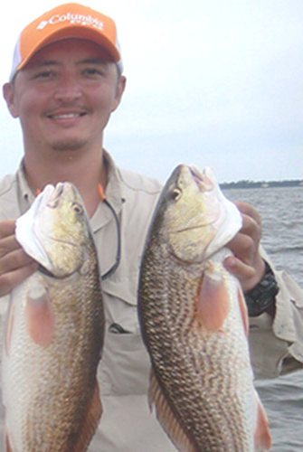 Angler holding two redfish