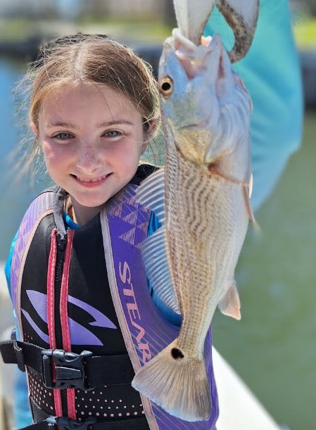 Young angler in a life jacket with her redfish