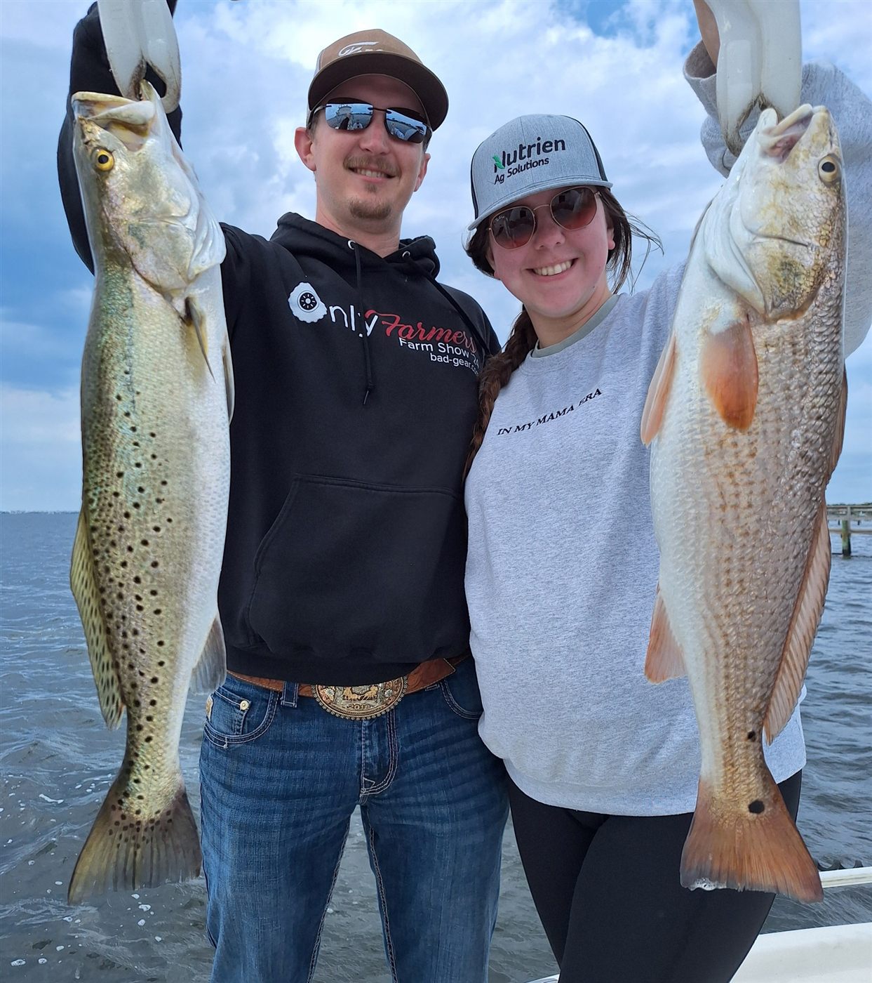 Two happy anglers holding a speckled trout and a redfish